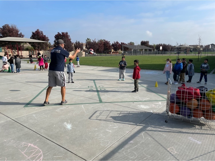 Mr. Black showing students at recess how yo play four square.